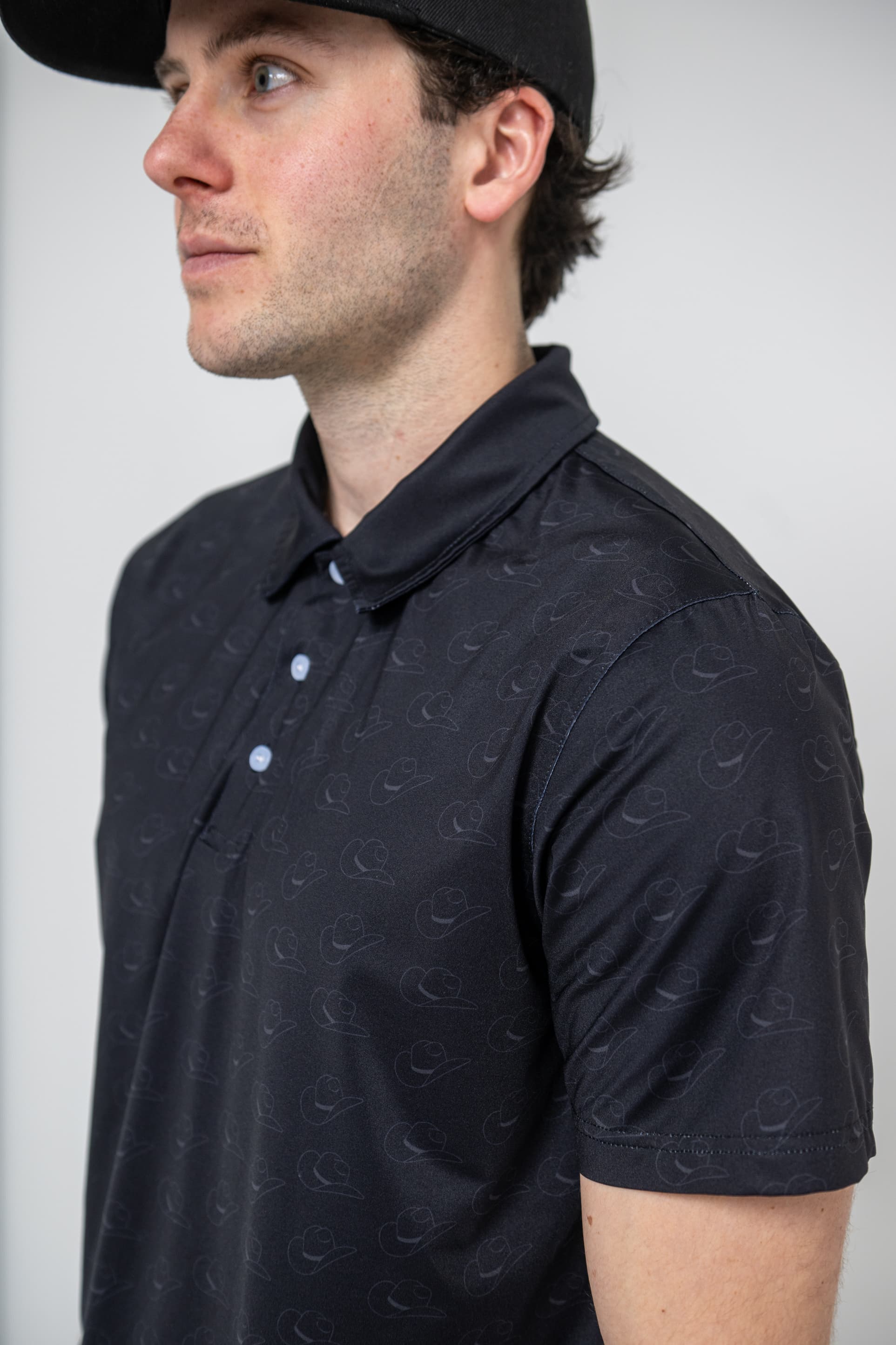 Gros plan d'un polo noir dont le motif ton sur ton est sublimé dans le tissu